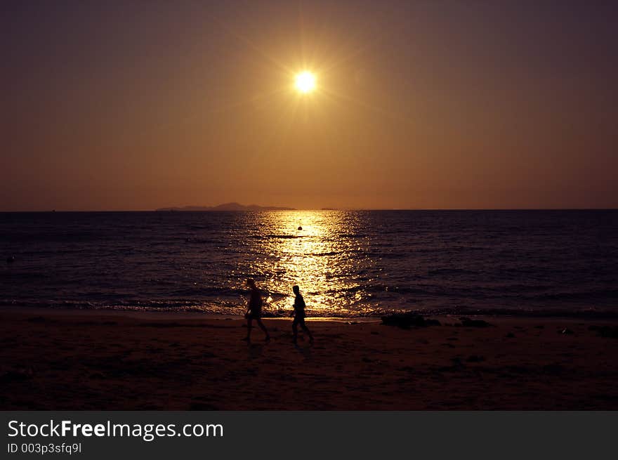 Two People walking agints sunset Location:Pattaya Beach, Thailand. Two People walking agints sunset Location:Pattaya Beach, Thailand