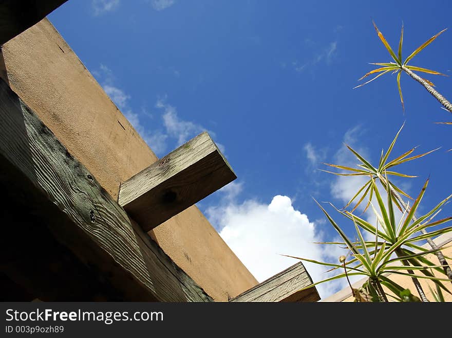 Broad sky and partial view of adobe structure and tropical plants. Broad sky and partial view of adobe structure and tropical plants.