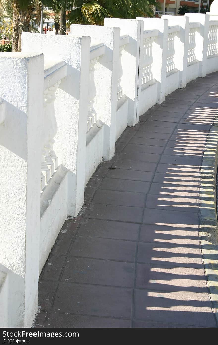 Decorative wall casting shadows across the path. Decorative wall casting shadows across the path