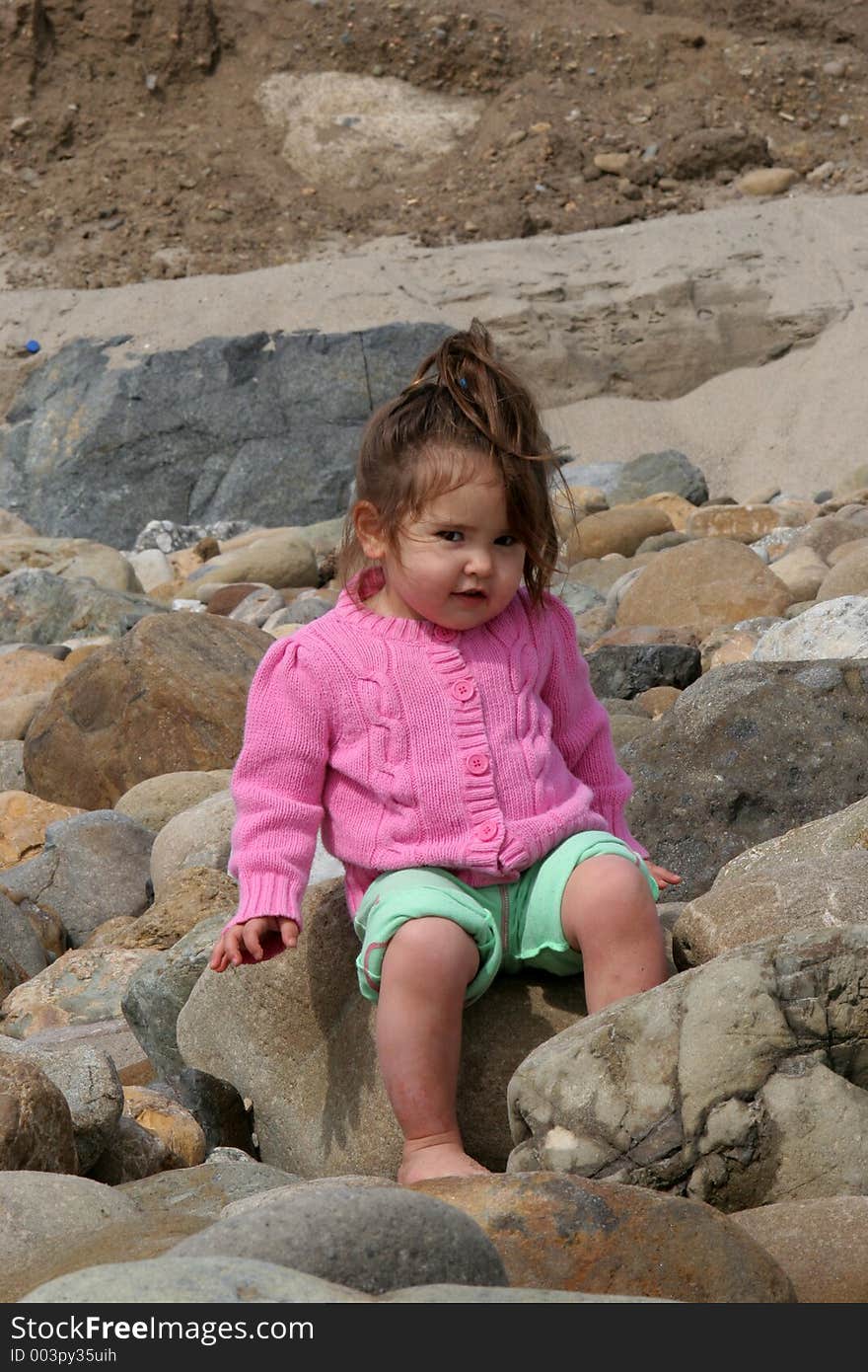 Child sitting on a rocky beach. Child sitting on a rocky beach