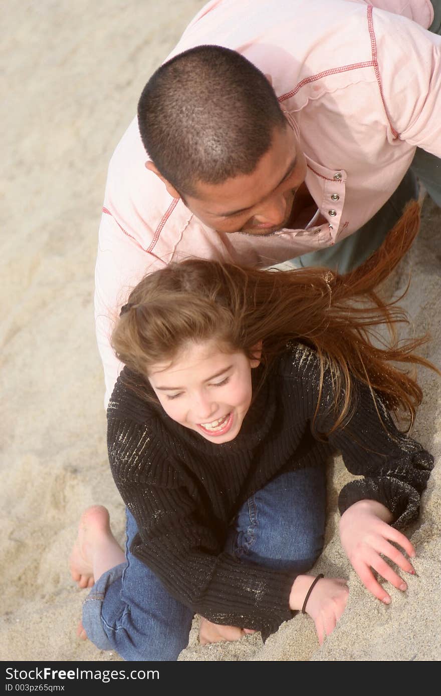 Father and Daughter rough housing in the Sand. Father and Daughter rough housing in the Sand.