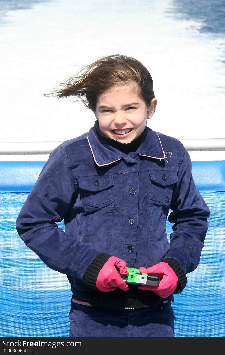 Young girl standing at the back of a boat, Holding a disposable Camera. Young girl standing at the back of a boat, Holding a disposable Camera