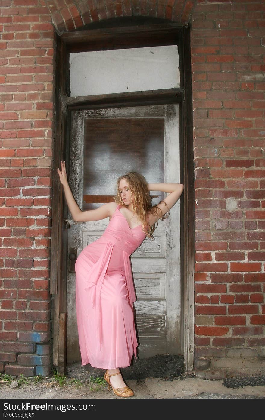 Beautiful young woman in formal dress standing in grunge doorway. Beautiful young woman in formal dress standing in grunge doorway.