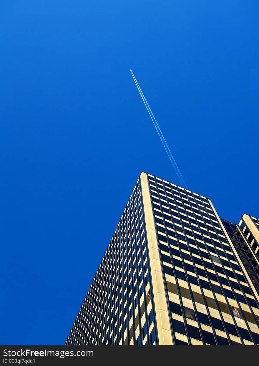 SkyCraper with plane and contrail in gorgeous blue sky. SkyCraper with plane and contrail in gorgeous blue sky.