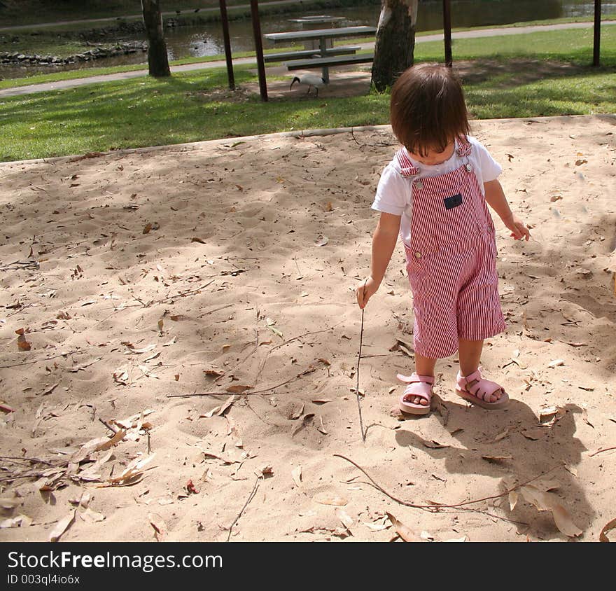 Toddler drawing in the sand with a stick