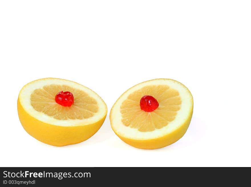 Two grapefruit halves with a red cherry on top of each, against a white background. Two grapefruit halves with a red cherry on top of each, against a white background.