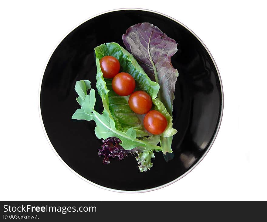 On a healthy diet. Isolated fresh leafy vegetables on a black plate. On a healthy diet. Isolated fresh leafy vegetables on a black plate.