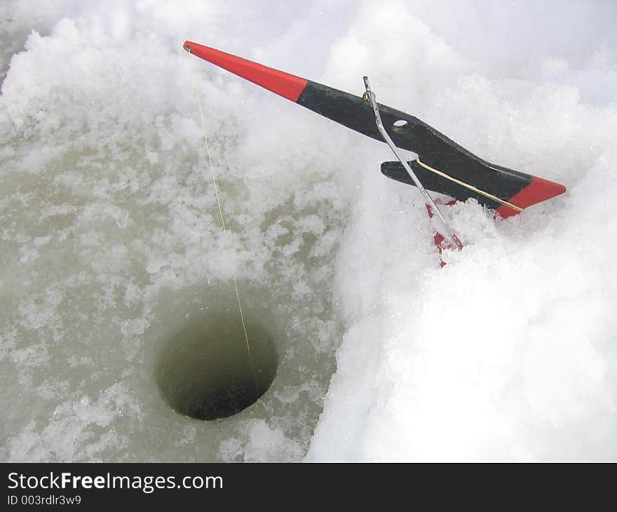 Home made ice fishing equipment and a fishing hole on a frozen lake