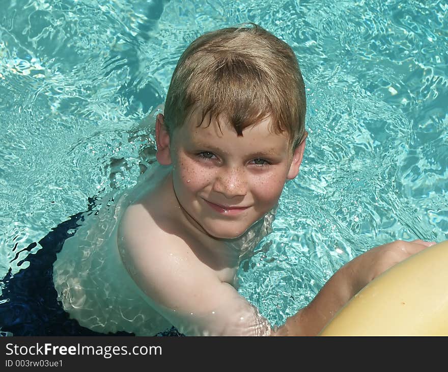 A close-up of a young boy swimming in a pool. A close-up of a young boy swimming in a pool.