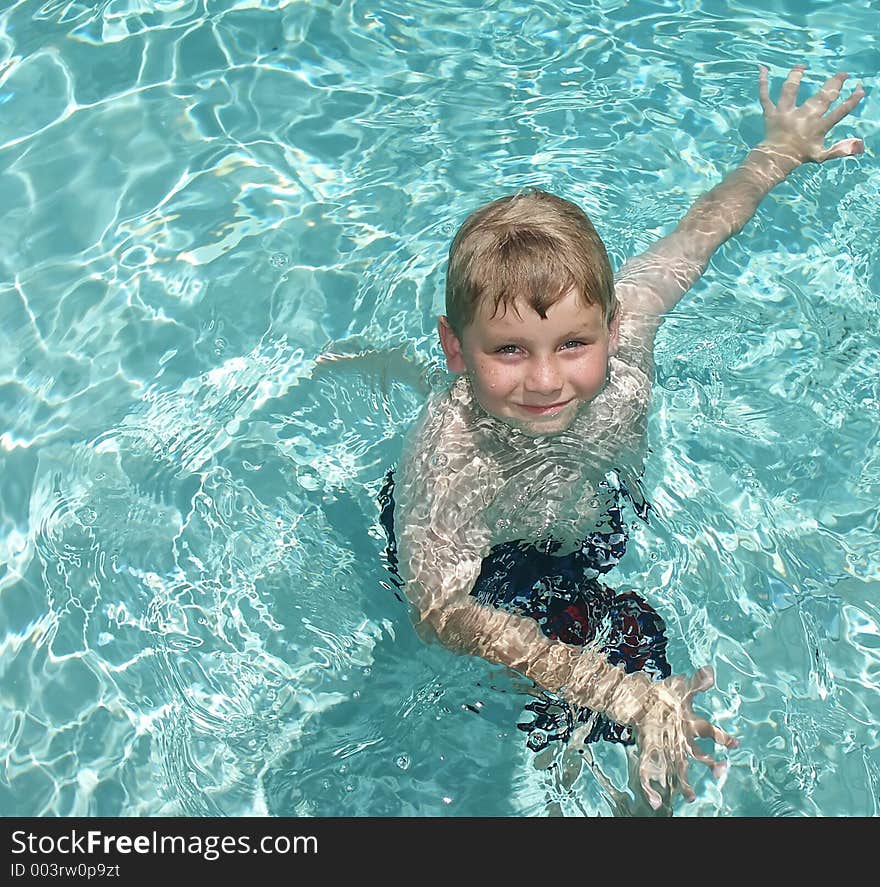 A young boy exercixing in a swimming pool. A young boy exercixing in a swimming pool.