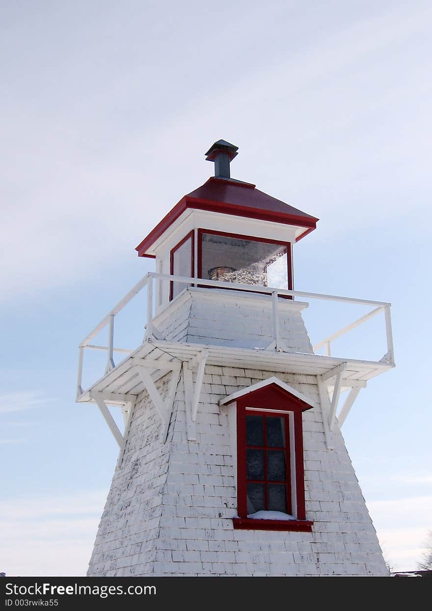 This image depicts a snow-covered lighthouse in a harbour.