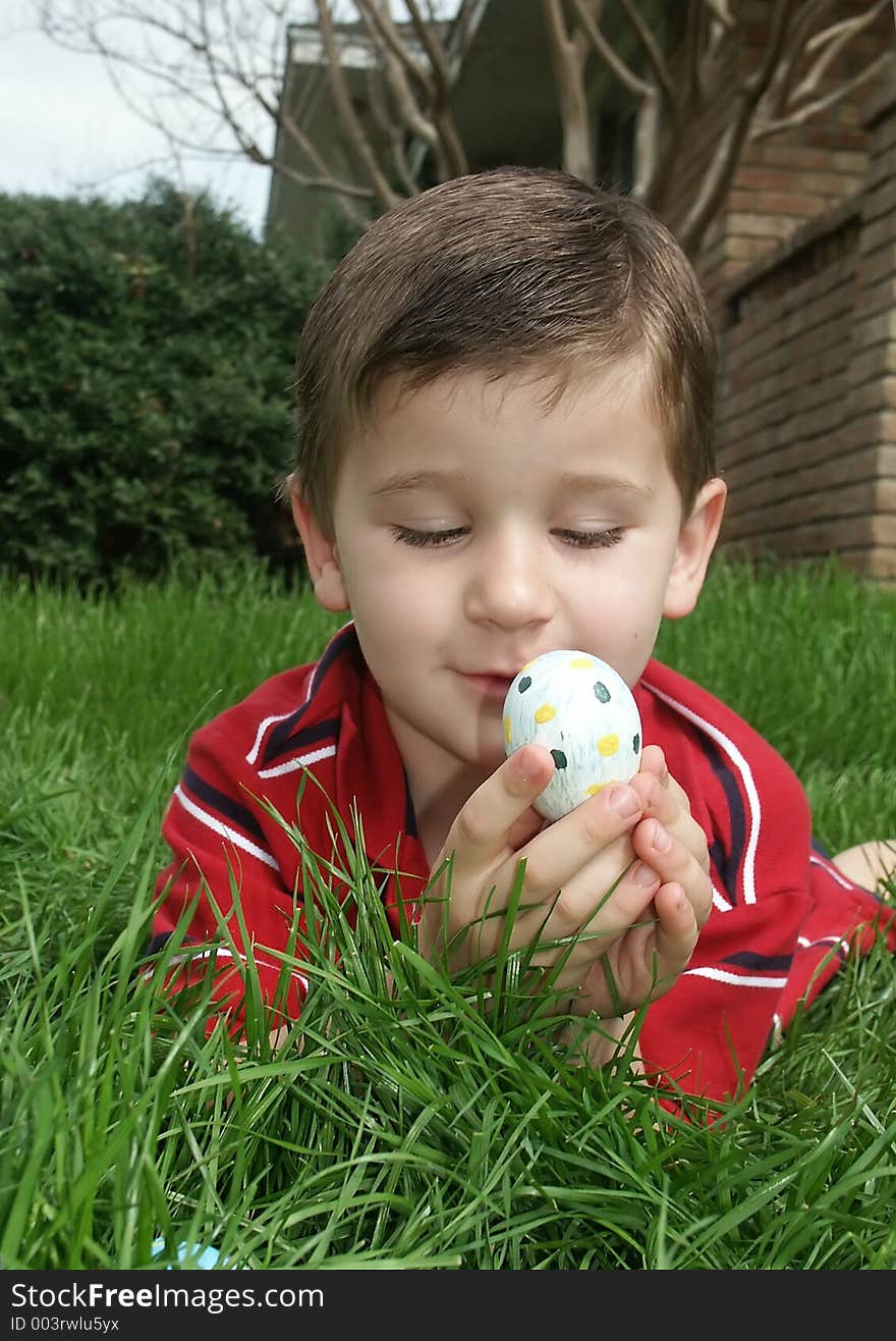 A young boy holding and inspecting a decorated Easter egg. A young boy holding and inspecting a decorated Easter egg.