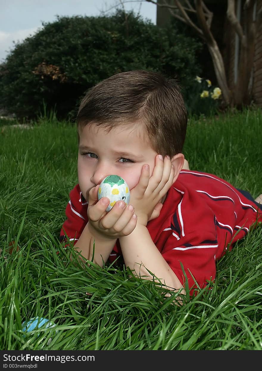 A youngboy looking unhappy while holding a decorated Easter egg. A youngboy looking unhappy while holding a decorated Easter egg.