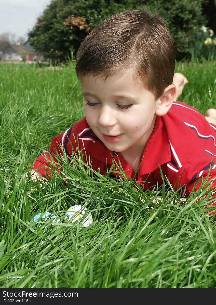 A young boy finding Easter eggs in the grass. A young boy finding Easter eggs in the grass.