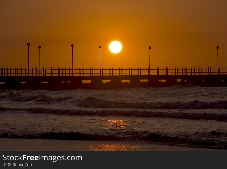 Orange Sunset over a Pier on a Beach. Orange Sunset over a Pier on a Beach