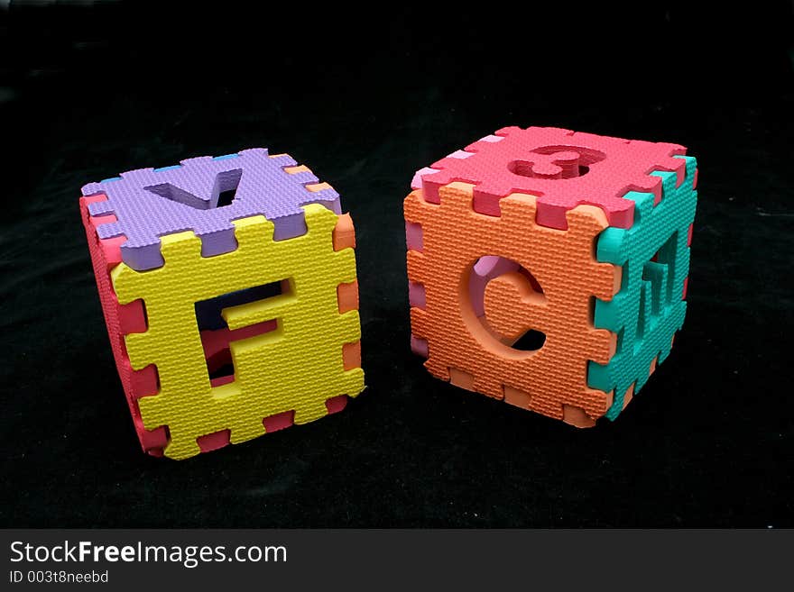 Puzzle cubes with letters and numbers over a black backgrund