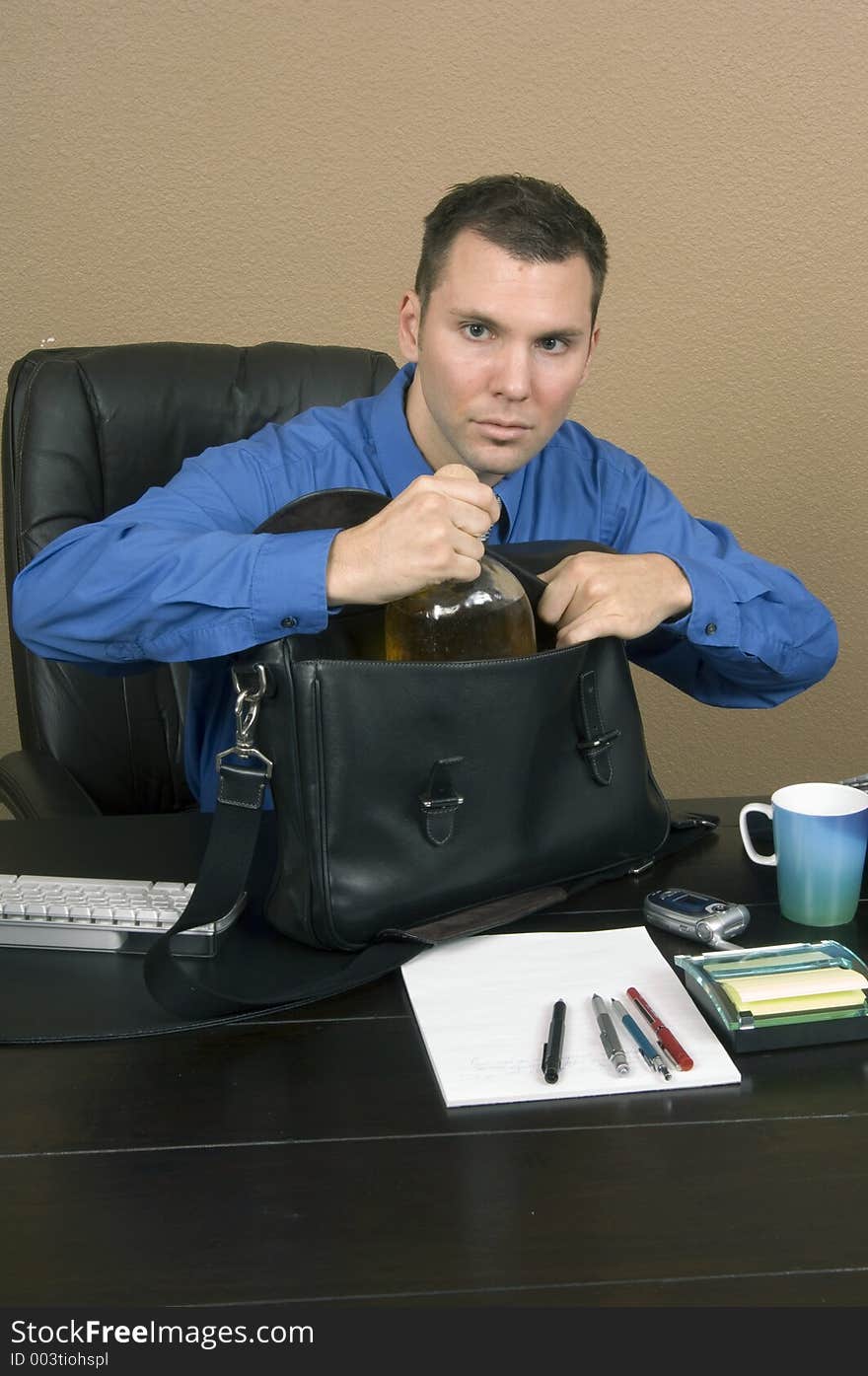 Employee smuggling some whiskey at his office in the working hours, happy about being able to pass through unnoticed. Employee smuggling some whiskey at his office in the working hours, happy about being able to pass through unnoticed