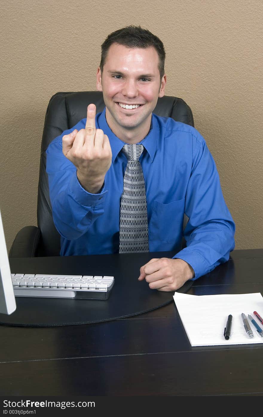 Angry employee giving the finger with a fake and forced smile on his face. Angry employee giving the finger with a fake and forced smile on his face