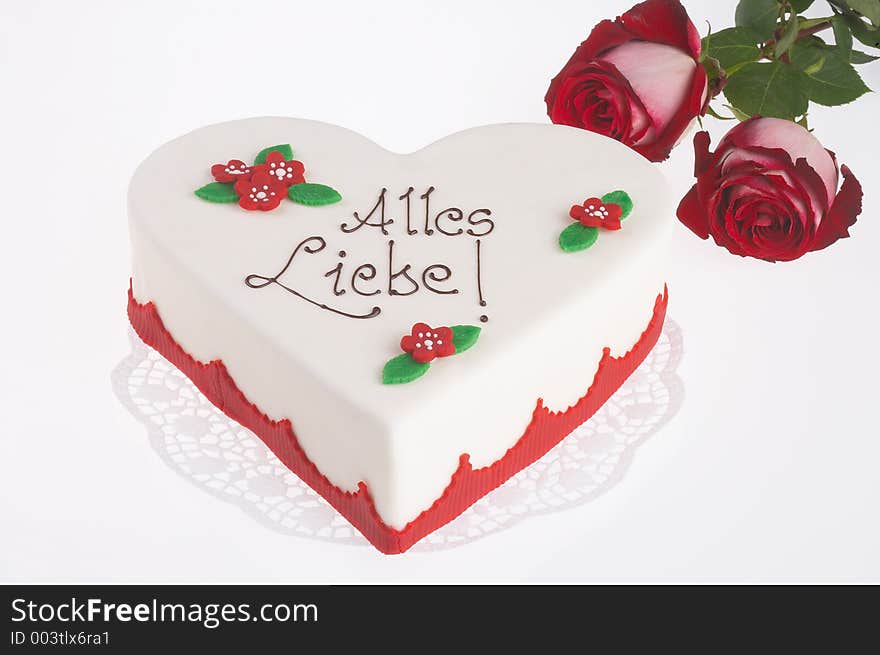 Heart shaped mothersday tart with two red roses next to it. Heart shaped mothersday tart with two red roses next to it