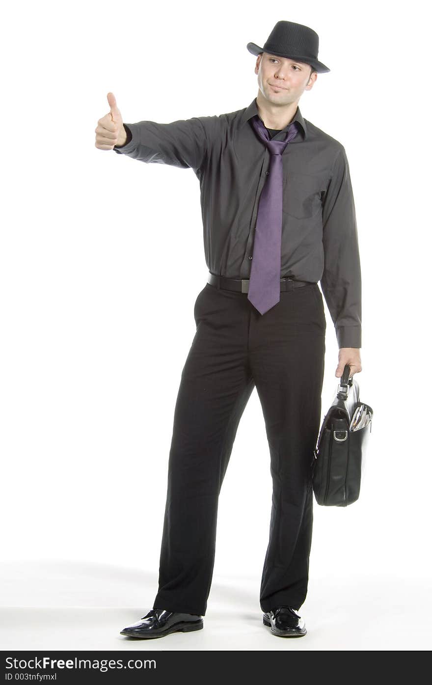 Young, attractive male model dressed soberly on tie, hat and briefcase hitch-hikes. Young, attractive male model dressed soberly on tie, hat and briefcase hitch-hikes