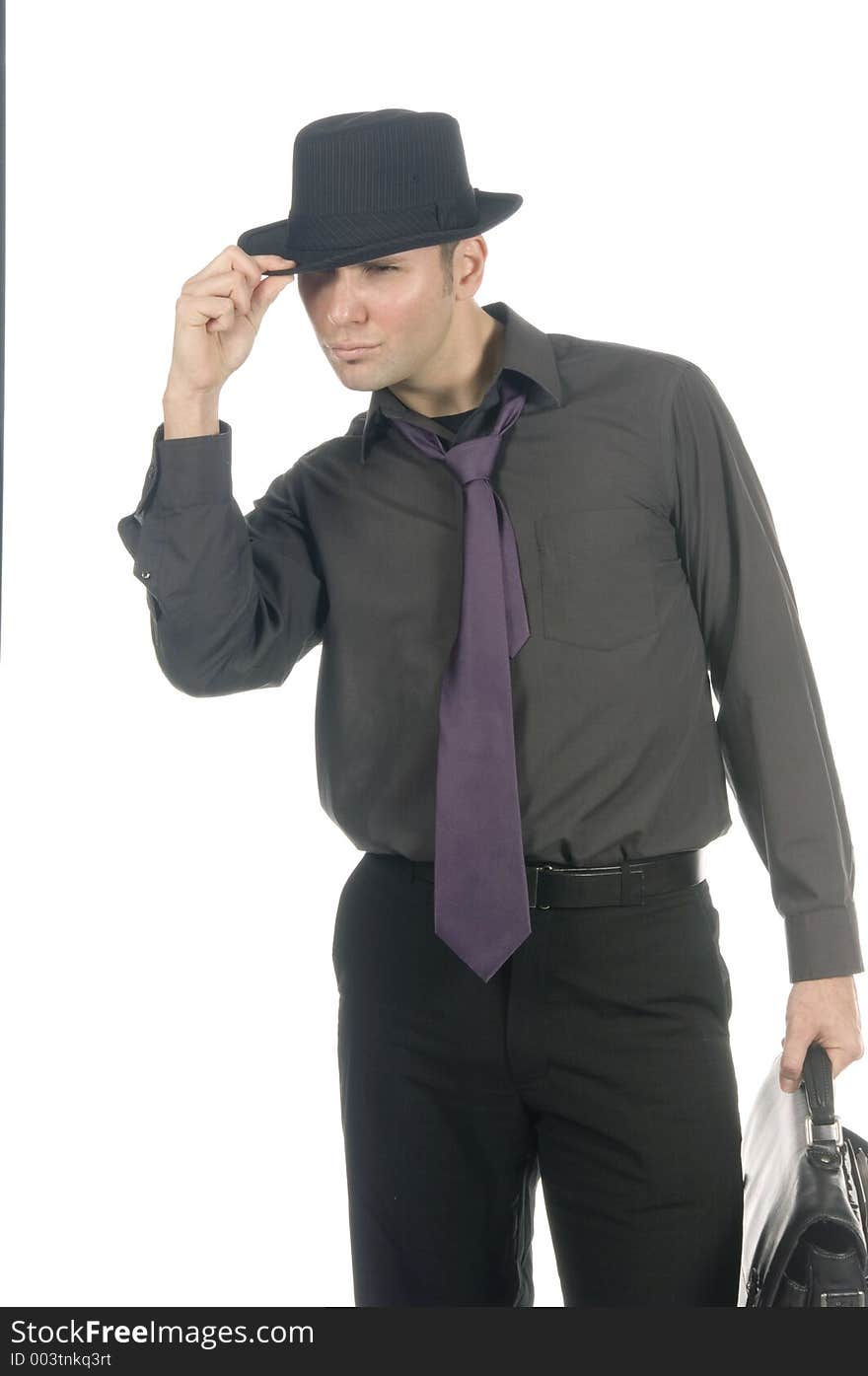 Young, attractive male model dressed soberly on tie, hat and briefcase poses in a cool stance over white. Young, attractive male model dressed soberly on tie, hat and briefcase poses in a cool stance over white