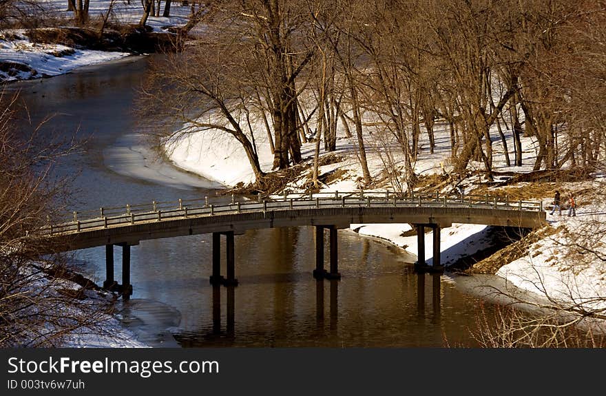 Two people on a walk through the park - about to cross a bridge. Two people on a walk through the park - about to cross a bridge