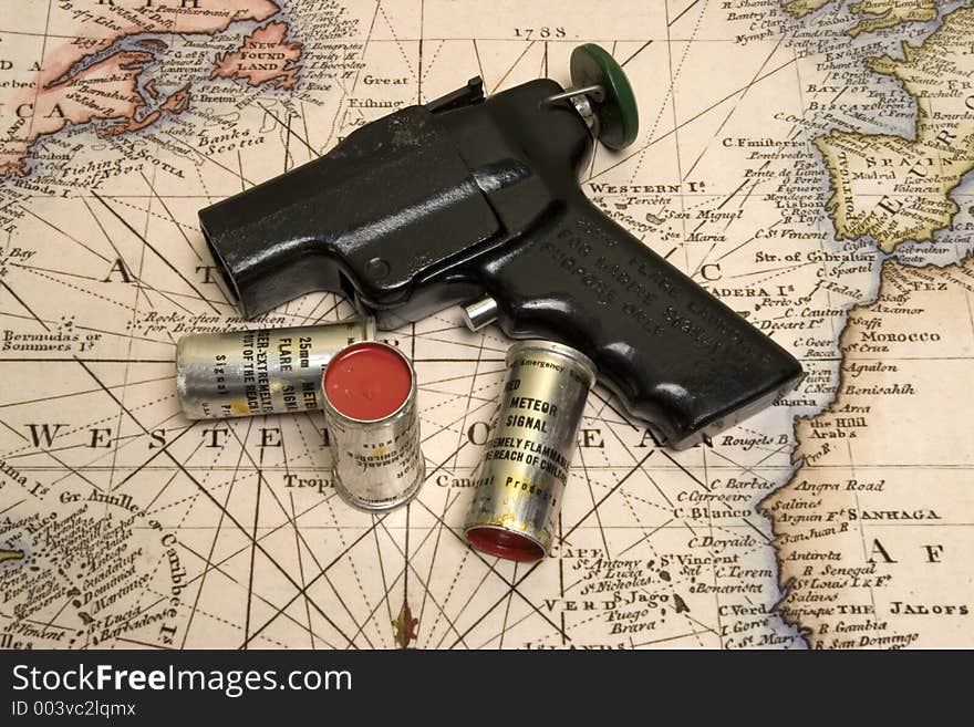 Signal flare gun and 3 rounds on top of old marine map. Signal flare gun and 3 rounds on top of old marine map