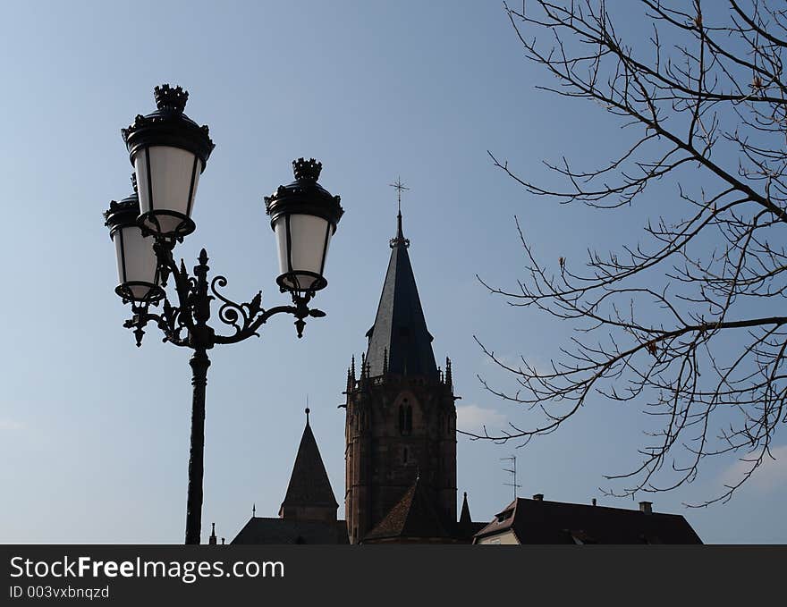 Three streetlamps on one lamppost on the way to Peter and Paul cathedral at the old town of Wissembourg in the Alsace area of France near the German border. Three streetlamps on one lamppost on the way to Peter and Paul cathedral at the old town of Wissembourg in the Alsace area of France near the German border