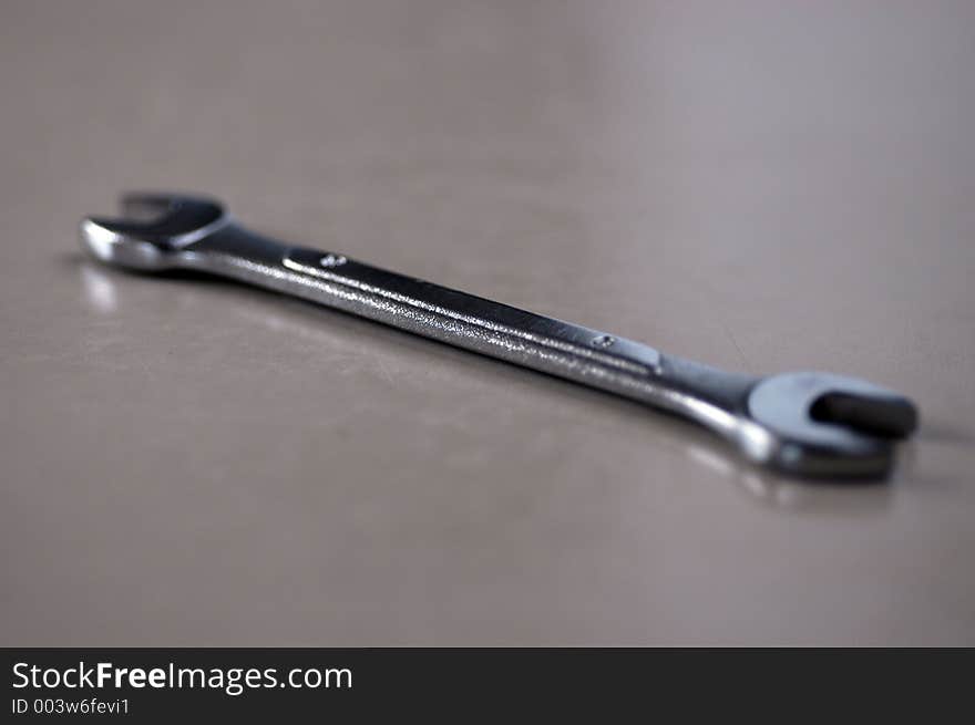 A shiny alloy open-ended auto wrench in shall DOF on a smooth surface