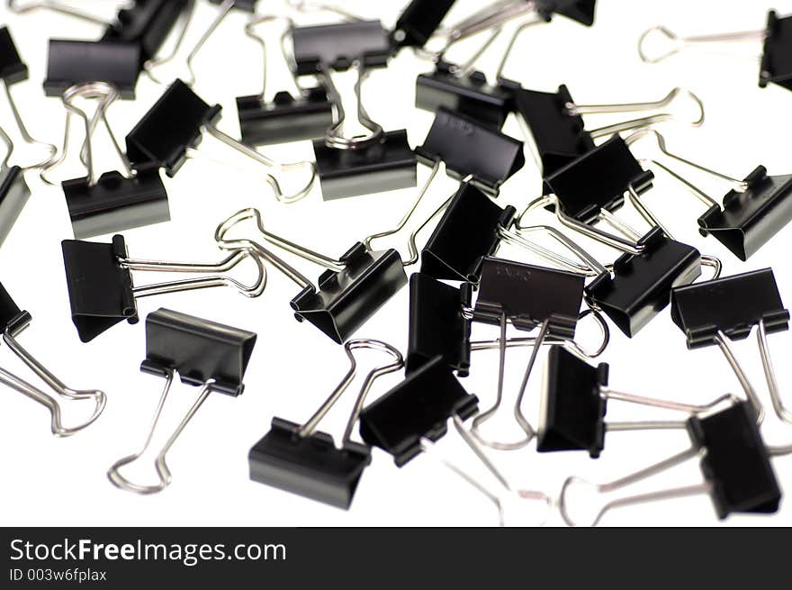 Many small binder clips scattered on a white surface