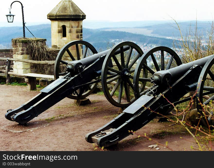 Two old cannons are standing on a court of a castle.