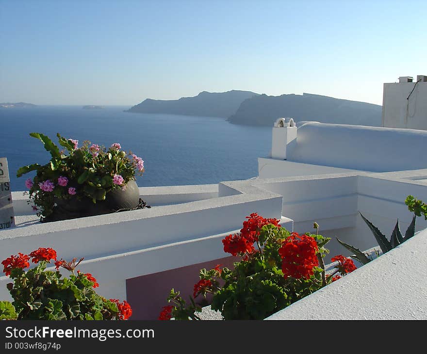 Red and pink geraniums, on an Aegean white house looking the blue sea. Red and pink geraniums, on an Aegean white house looking the blue sea.