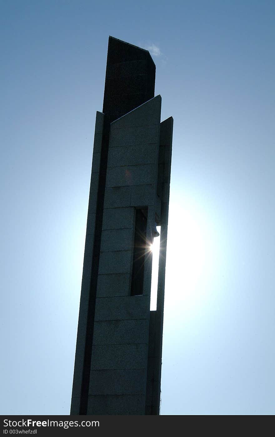 Image of a bell tower with the sun behind it, causing a sunburst effect as it shines through a gap in the building. Image of a bell tower with the sun behind it, causing a sunburst effect as it shines through a gap in the building.