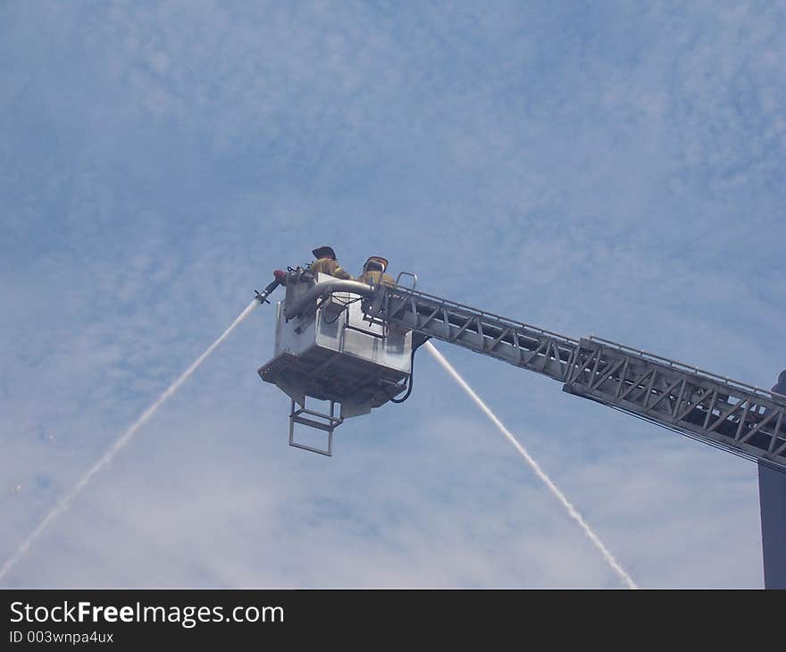 Two fireman try to tame a vicious fire. Two fireman try to tame a vicious fire