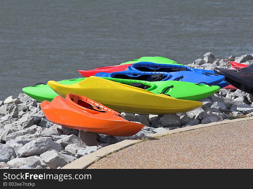 Line of colorful kayaks on bank waiting for use