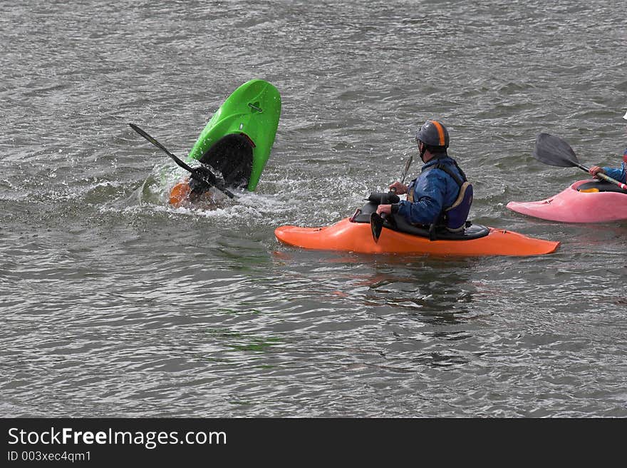 Kayaker practicing recovery from roll over with trainer watching. Kayaker practicing recovery from roll over with trainer watching