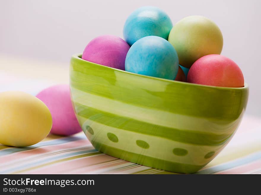 Bowl of Easter eggs in large green bowl sitting on stripped placemat. Bowl of Easter eggs in large green bowl sitting on stripped placemat.