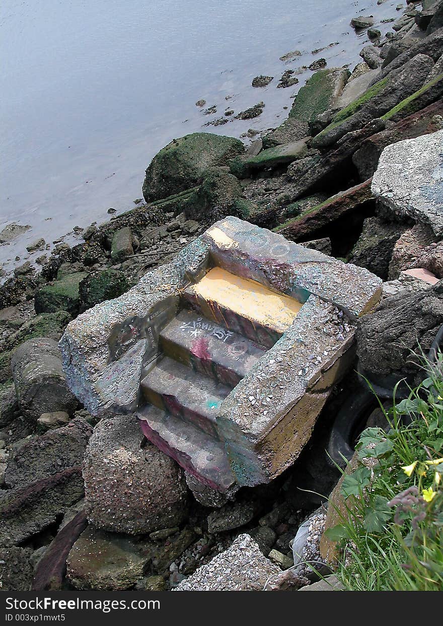 Steps cast in concrete long separated from their original location and sitting among industrial debris in a dock area. Steps cast in concrete long separated from their original location and sitting among industrial debris in a dock area