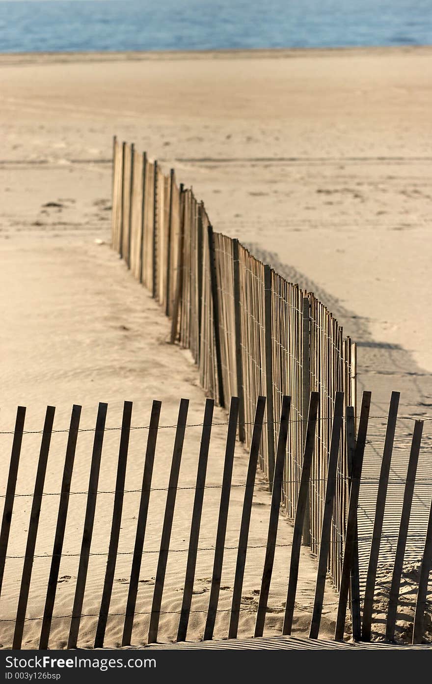 Ocean beach with a wood picket fence. Small portion of the fence is in focus. Ocean beach with a wood picket fence. Small portion of the fence is in focus.