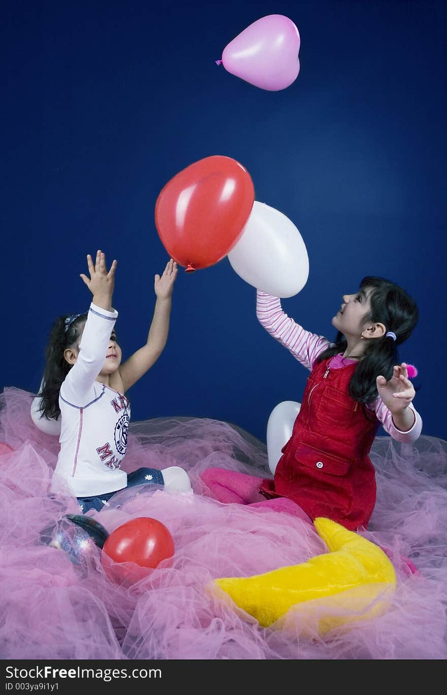 Young and beautiful girls playing with white and pink balloons. Young and beautiful girls playing with white and pink balloons