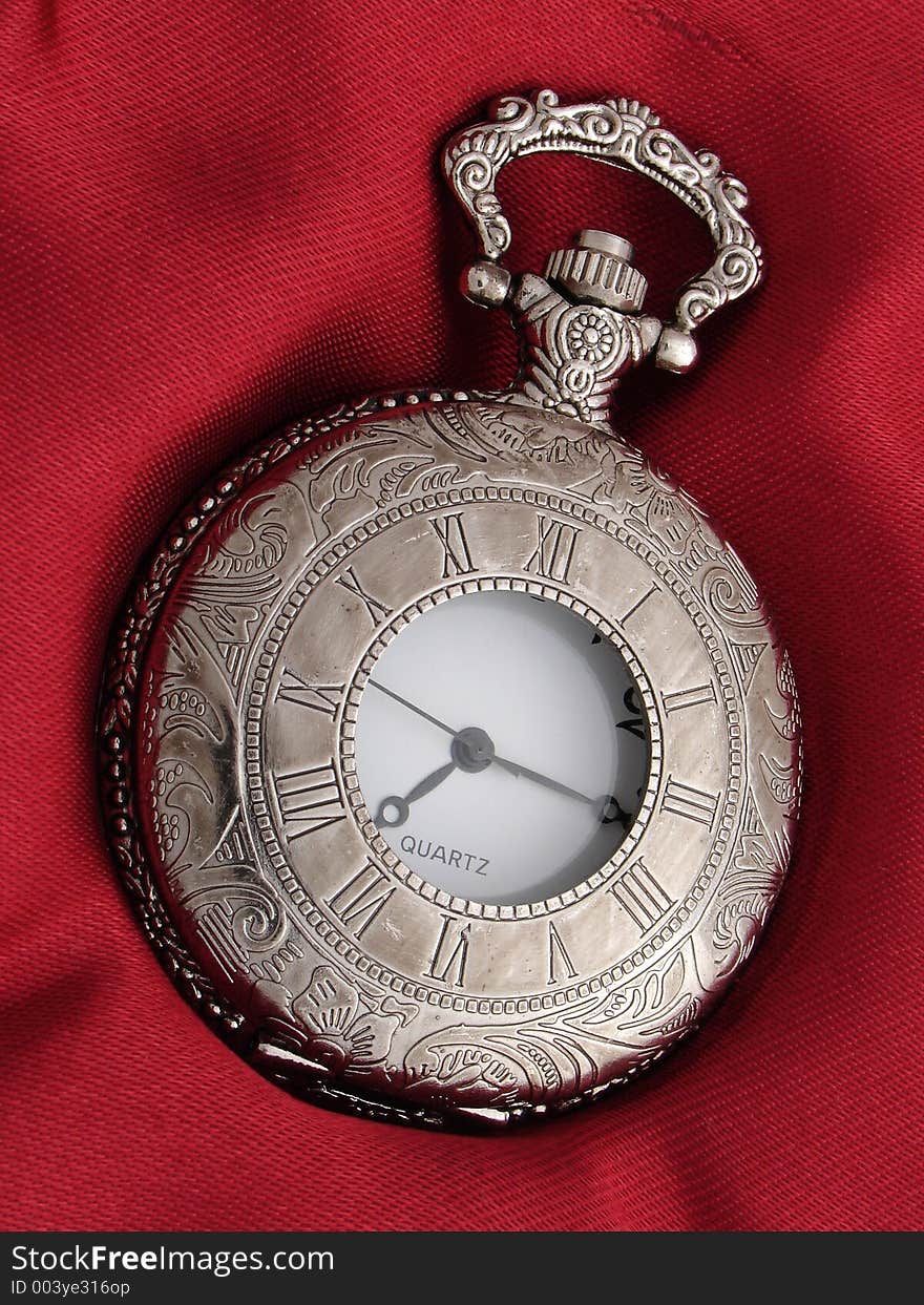 Silver pocket watch on red silk background