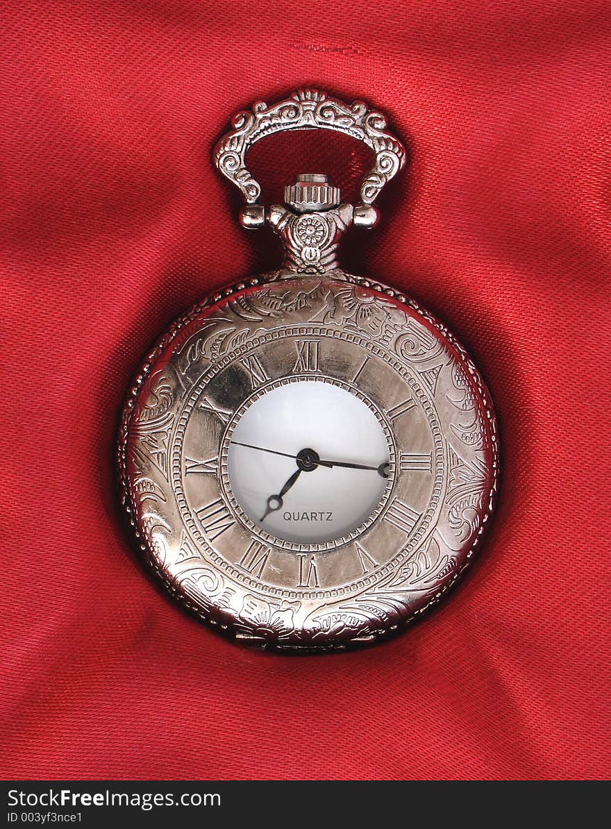 Silver pocket watch on red silk background