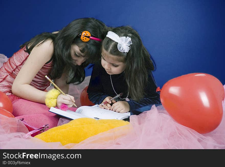 Two little girls writing in a big agenda. Two little girls writing in a big agenda