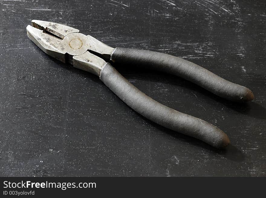 A pair of pliers on a black surface. A pair of pliers on a black surface