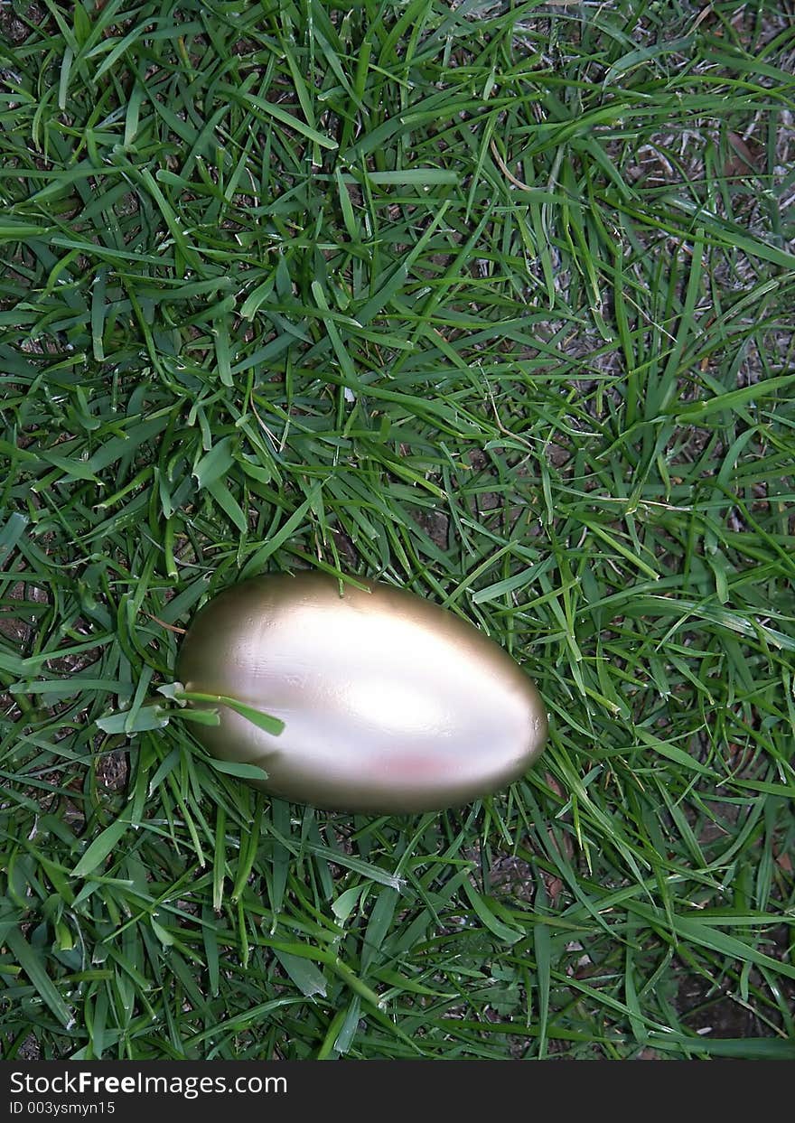 A golden egg laying in bright green rye grass.