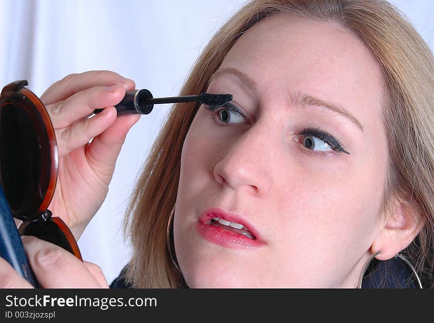 A woman applying mascara. A woman applying mascara.