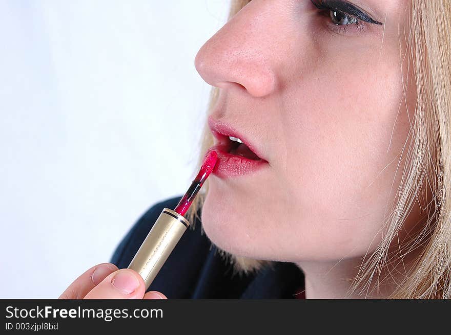 A woman applying lipstick. A woman applying lipstick.