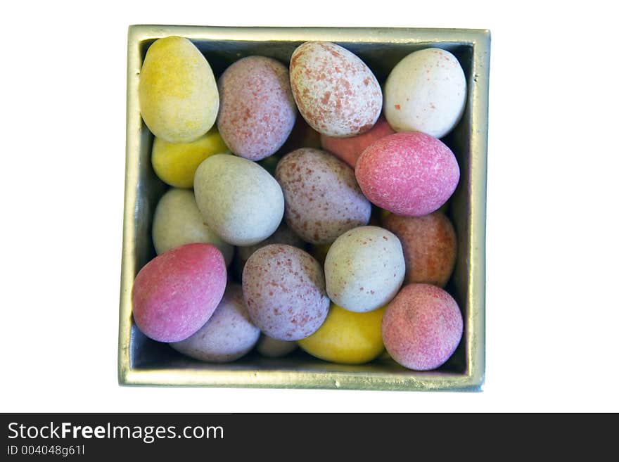 Mini candy chocolate eggs in a polished silver box, viewed from above, isolated on white. Mini candy chocolate eggs in a polished silver box, viewed from above, isolated on white