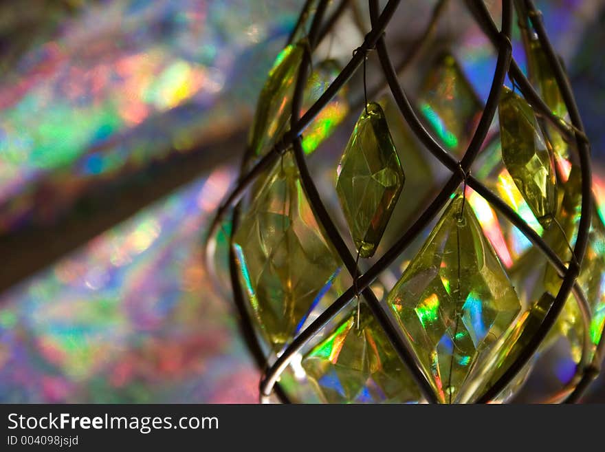 Sun shining through gorgeous green, teardrop crystal makes a kaleidoscopic pattern in the background. Sun shining through gorgeous green, teardrop crystal makes a kaleidoscopic pattern in the background.