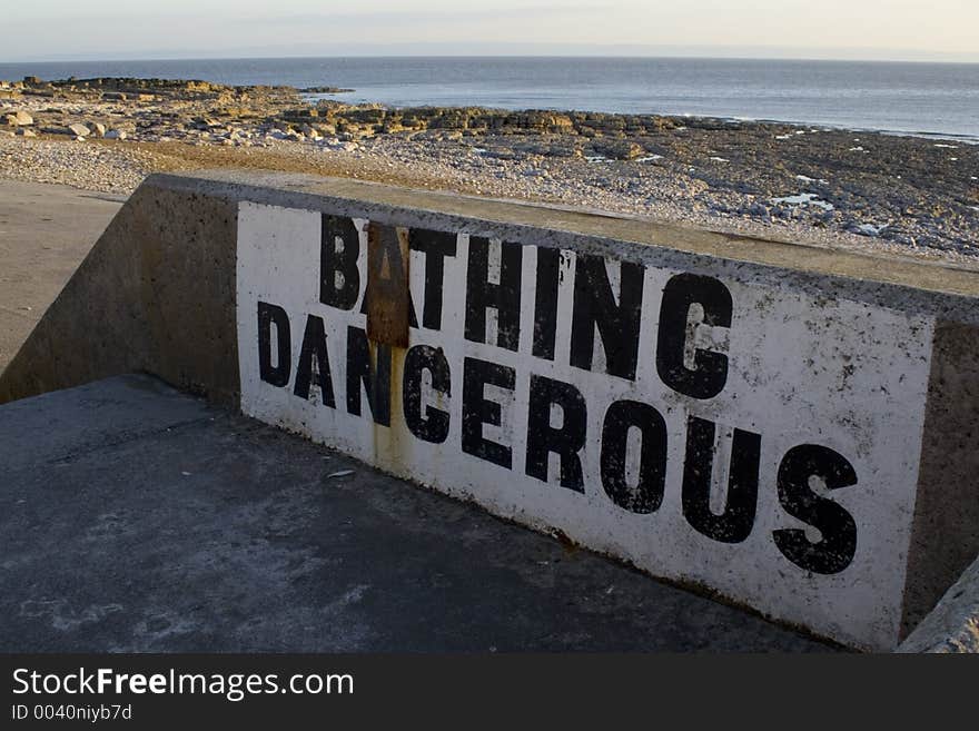 Weathered warning painted onto sea wall at Porthcawl, South Wales, UK. Weathered warning painted onto sea wall at Porthcawl, South Wales, UK